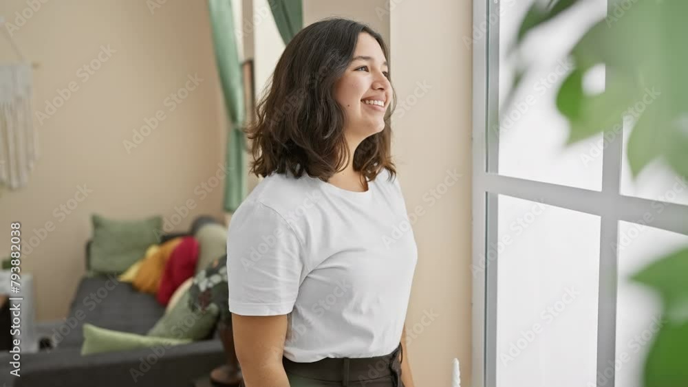 Confident young hispanic woman, casually standing, relaxed side-profile pose in her home, beaming with a natural smile. Confident young hispanic woman, casually standing, relaxed side-profile pose in her home, beaming with a natural smile.