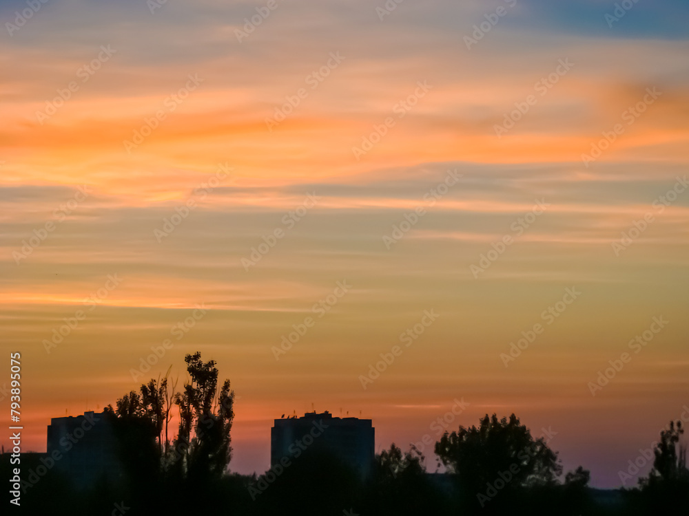 
Sunset in the city with silhouettes of buildings.