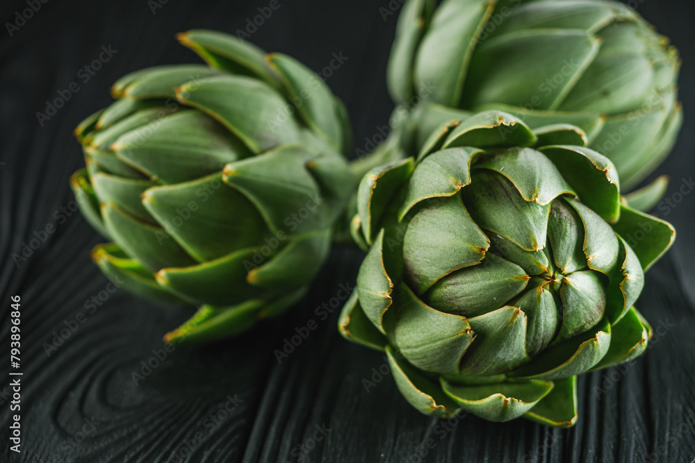 Fototapeta premium fresh natural artichokes on a black wooden background