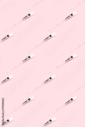Pattern made of makeup brush with transparent handle on a pink background. Creative layout.