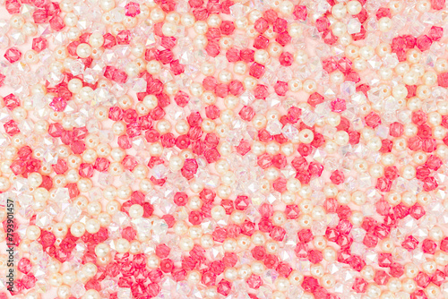 Texture made from various acrylic beads scattered on a pink background.