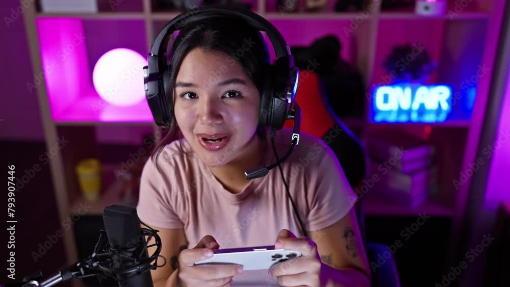 Hispanic woman enjoying video gaming at night in a colorful illuminated room. Hispanic woman enjoying video gaming at night in a colorful illuminated room.