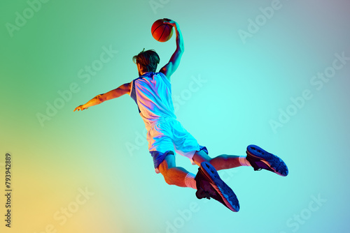 Competitive man, athlete in motion, training, playing basketball against gradient background in neon light. Concept of sport, competition, active and healthy lifestyle, game © master1305