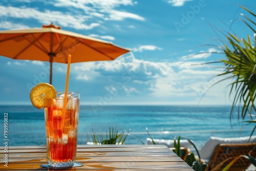 Refreshing iced drink on a table with ocean and beach umbrella in background. © vachom