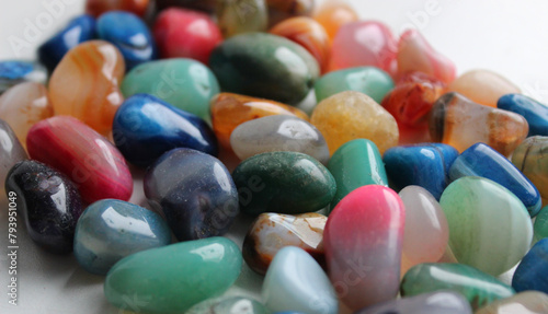 Heap of raw glance semi precious colored stones on a white surface closeup angle view
