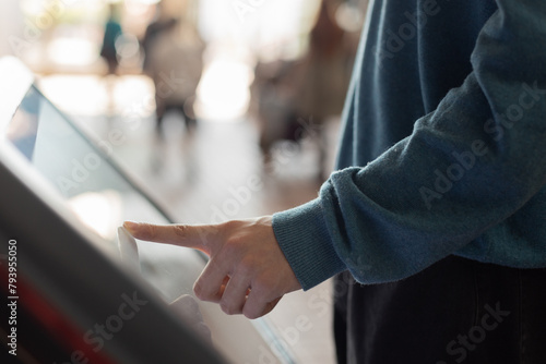 man at self service transfer area doing self-check-in or buying plane tickets at automated machine with touchscreen interactive display in modern airport terminal building © Leka