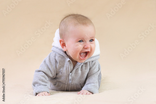 Cute joyful baby on a beige background.