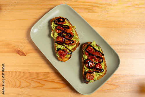 Tableau sur toile A plate of bruschettas topped with vibrant guacamole and cherry tomatoes sits on a restaurant table