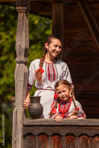 mother and daughter dressed in Ukrainian national costumes look at the camera