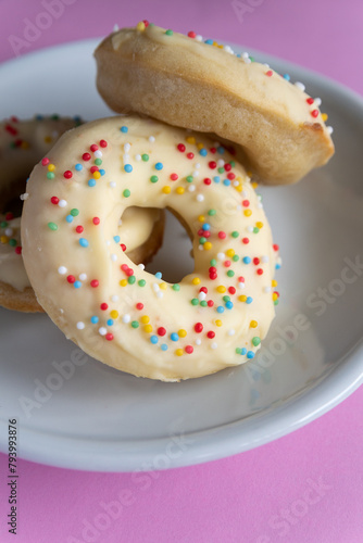 Small homemade donuts covered in white chocolate and colorful toppings