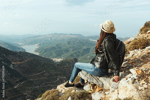 Woman traveler sitting on a rock and looking to the horizon.