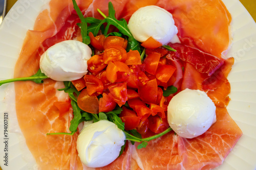 Cuisine of Emilia-Romagna region, Caprese salad with Prosciutto crudo, prosciutto di Parma, mozzarella cheese and tomatoes, lunch in Parma, Italy photo