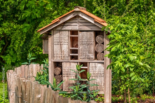 One wooden insect house in the garden. Bug hotel at the park with plants.