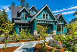 A newly built, vivid teal craftsman cottage style home, with a triple pitched roof, lush landscaping, a clear pathway, and eye-catching curb appeal that sets a new standard for residential design.