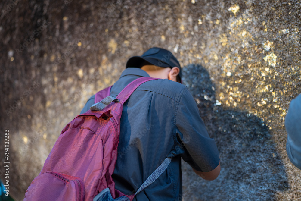 Male tourists pay their respects by covering the giant rocks with gold leaf at Khao Khitchakut National Park, Chanthaburi, Thailand. Male tourists pay their respects by covering the giant rocks with gold leaf at Khao Khitchakut National Park, Chanthaburi, Thailand.