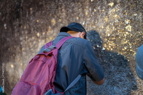 Male tourists pay their respects by covering the giant rocks with gold leaf at Khao Khitchakut National Park, Chanthaburi, Thailand.