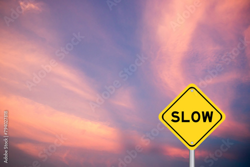 Yellow transportation sign with word slow on violet color sky background photo