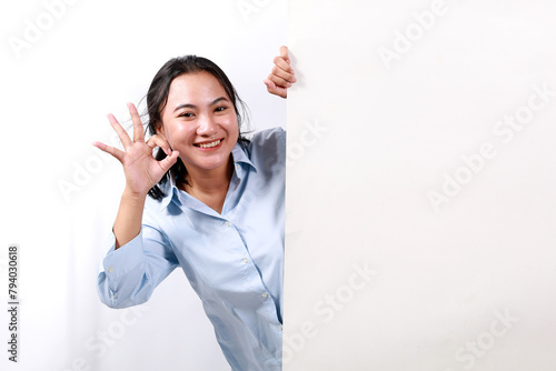 Happy smiling beautiful young woman showing blank signboard or copyspace for slogan or text while making okay hand gesture, isolated over white background