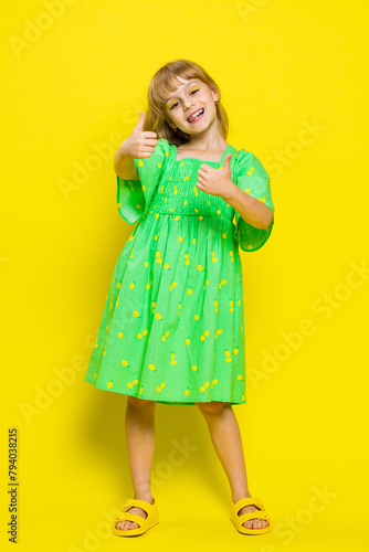 Like. Happy preteen child girl kid looking approvingly at camera showing thumbs up, like sign positive something good, positive feedback great news. Children isolated on yellow background. Vertical
