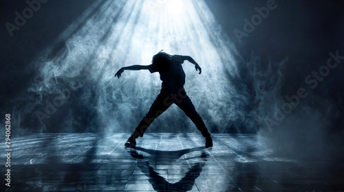 Hip Hop dancer dancing on a stage in dark colors. The young man is likely showcasing his dancing skills in a performance setting. Modern dance, clothing, performance art, and music. photo