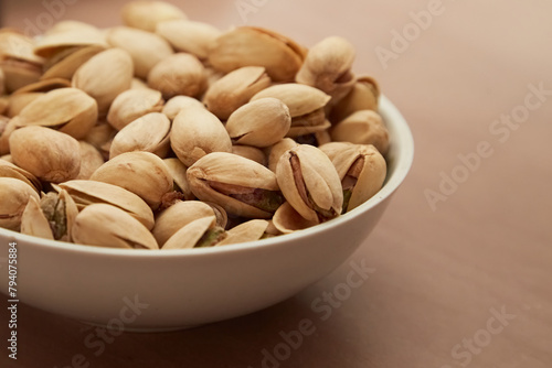 Pistachios in a white bowl on the table, pistachios snack for beer, salted pistachios, close-up