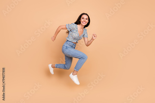 Photo of funky carefree cheerful woman wear blue trendy clothes run fast empty space isolated on beige color background