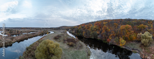 Aerial panorama of river curve with autumn forest and grey cloudy sky in Ukraine