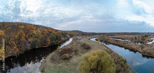 Aerial trees on river curve panorama with autumn forest and grey cloudy sky in Ukraine