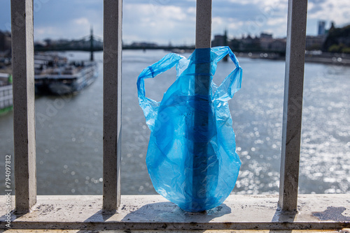 Blue Plastic bag hanging on the railing of Elisabeth bridge over Donau river in Budapest. Garbage in the city. Environmental pollution concept. Ecological disaster, catastrophe. Selective focus photo