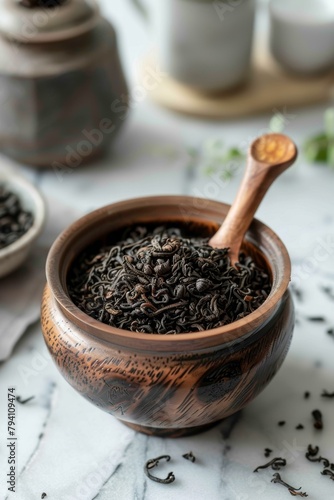 Black tea leaves in a wooden bowl with a wooden spoon