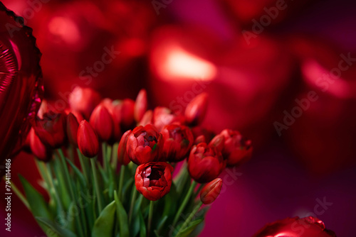 A bouquet of tulips on a background of balloons of red hearts.