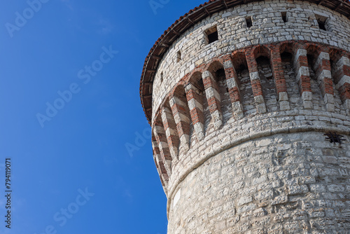 The historical Torre dei Prigionieri in Brescia castle, captured in bright daylight, showcases its intricate brickwork and stonemasonry, reflecting Italian medieval castle design photo