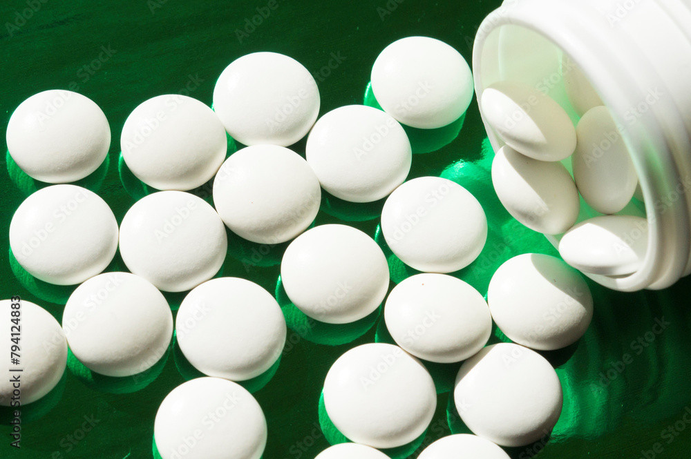white pills on a green shiny background white pills on a green shiny background