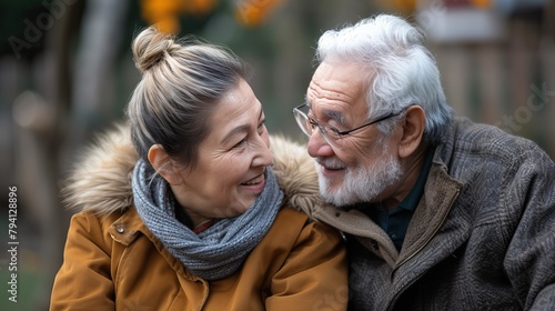 Affectionate senior couple sharing a joyful moment outdoors, with warm smiles and a cozy autumnal backdrop, showcasing timeless love and companionship.