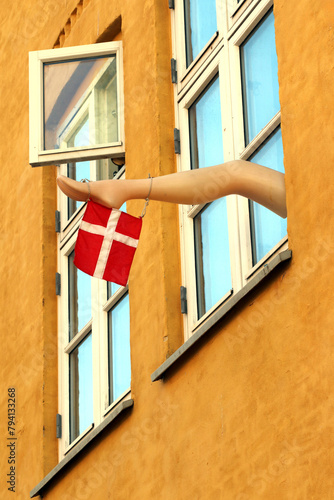Mannequins leg is attached to one window. The Danish flag hangs on the plastic leg of a mannequin.