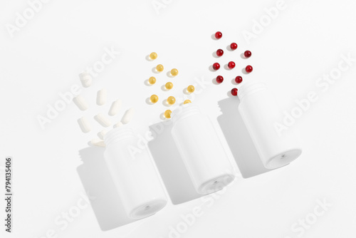 Three mockup jars with white, yellow and red pills capsules at an angle on a white isolated background. The concept of health, medicines, pharmacy. Image for your design