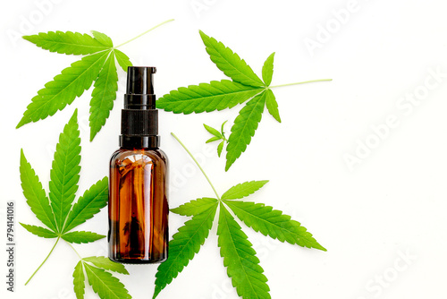 Marijuana leaves and a bottle on a white background, cannabis cosmetic oil