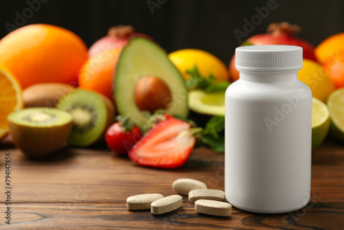 Vitamin pills, bottle and fresh fruits on wooden table. Space for text