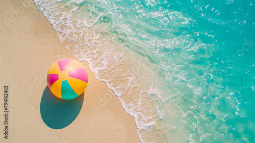 Aerial view of a beach with clear waters and a vibrant beach ball on sand