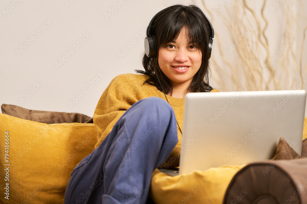 A woman is sitting on a couch with a laptop in front of her A woman is sitting on a couch with a laptop in front of her
