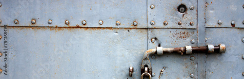 Fotografie A fragment of an old gate, which is covered with iron