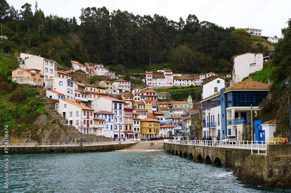 Cudillero is a small, picturesque fishing port nestled on the side of a mountain. Its hanging houses stand out with eaves and brightly colored windows that are located in a steep horseshoe of cliffs