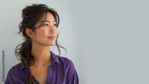 Asian woman wearing purple shirt smile looking up isolated on gray