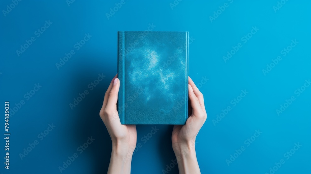 Creative theme captured in an advertising photo of a hand holding a notebook, vibrant blue background, inspiring imagination and ideas Creative theme captured in an advertising photo of a hand holding a notebook, vibrant blue background, inspiring imagination and ideas