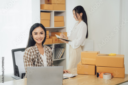 Starting small businesses SME owners female entrepreneurs Use a laptop or notebook to receive and review orders online to prepare to pack boxes, sell to customers, online sme business ideas. © Wicitr