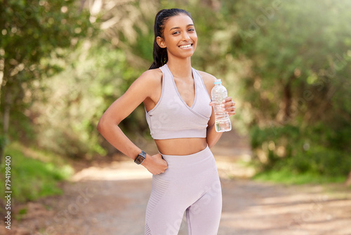 Woman, bottle and outdoor in portrait with smile for exercise, workout or running in the forest. Happy, female person or athlete in nature for fitness, training and health with water drink to relax © peopleimages.com