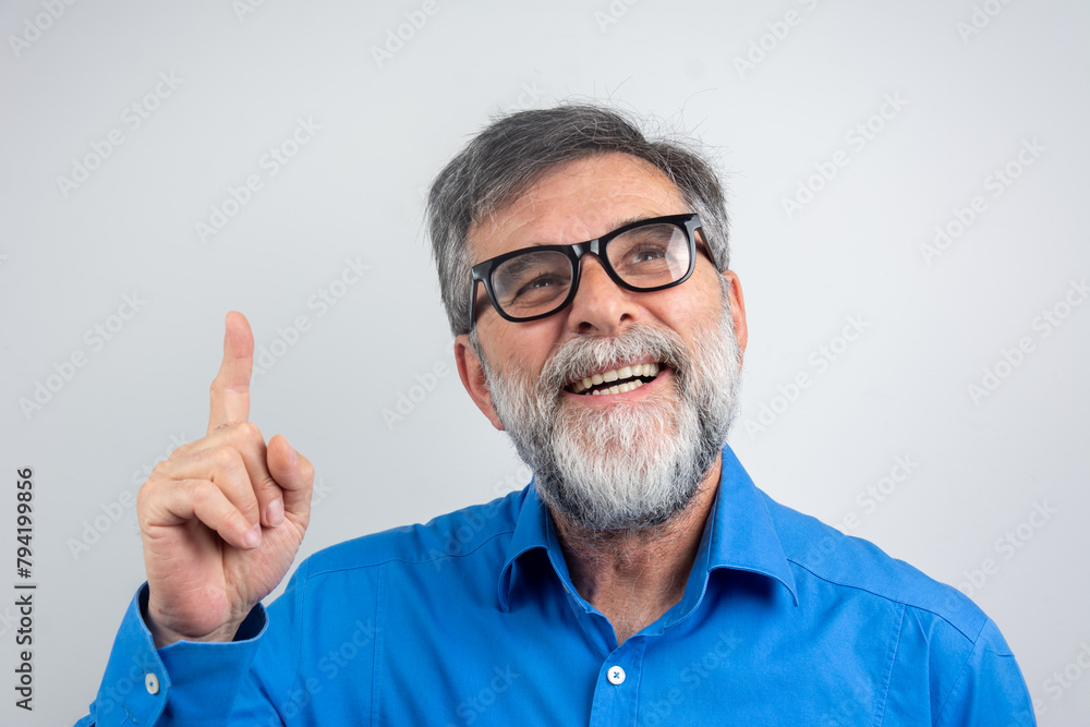 Mature handsome man with beard wearing casual shirt and glasses over grey background Smiling pointing to head with one finger, great idea or thought, good memory Mature handsome man with beard wearing casual shirt and glasses over grey background Smiling pointing to head with one finger, great idea or thought, good memory