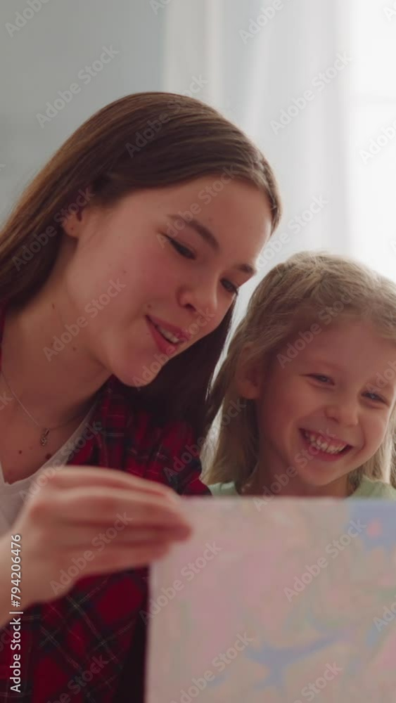 Joyful teenage girl with admired sister look at painting in Ebru style in apartment closeup slow motion. Traditional marbling design technique for family Joyful teenage girl with admired sister look at painting in Ebru style in apartment closeup slow motion. Traditional marbling design technique for family