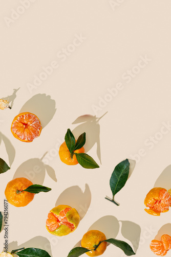 Fresh tangerines on beige background with sunlight shadows  minimal aesthetic citrus fruits as summer food background  organic orange colored mandarin with green leaves top view  copy space