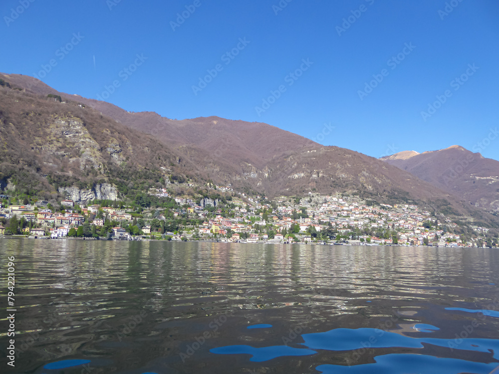 Panoramic view from a boat of city and lake of Como, Lomardy, Italy, Europe. Yachting on alpine mountain lake in the Italian Alps in summer. Living luxury life style, architecture and travel concept